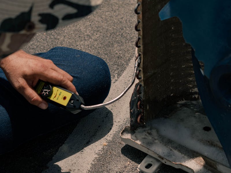Technician servicing outdoor air conditioning unit on a sunny day