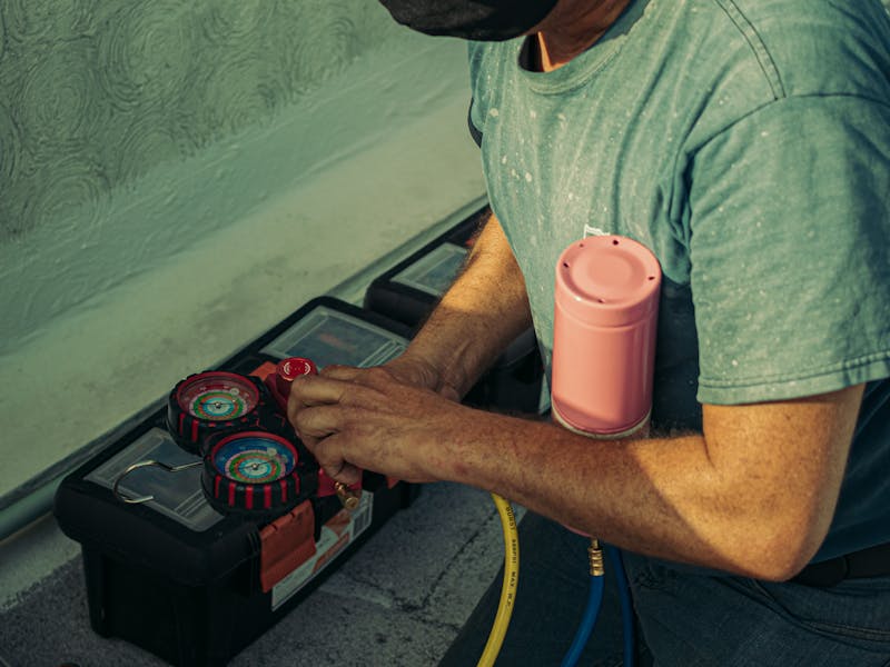 HVAC professional performing routine air conditioner maintenance and tune-up